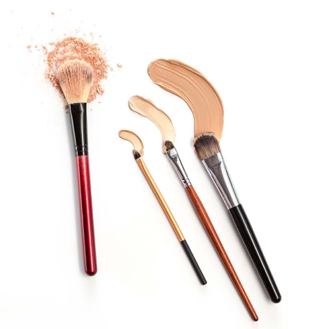 Close-up of crushed mineral shimmer powder golden color with makeup brush on white background with Cosmetic foundation cream