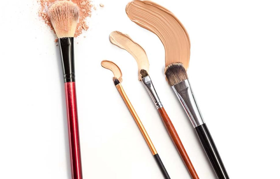 Close-up of crushed mineral shimmer powder golden color with makeup brush on white background with Cosmetic foundation cream